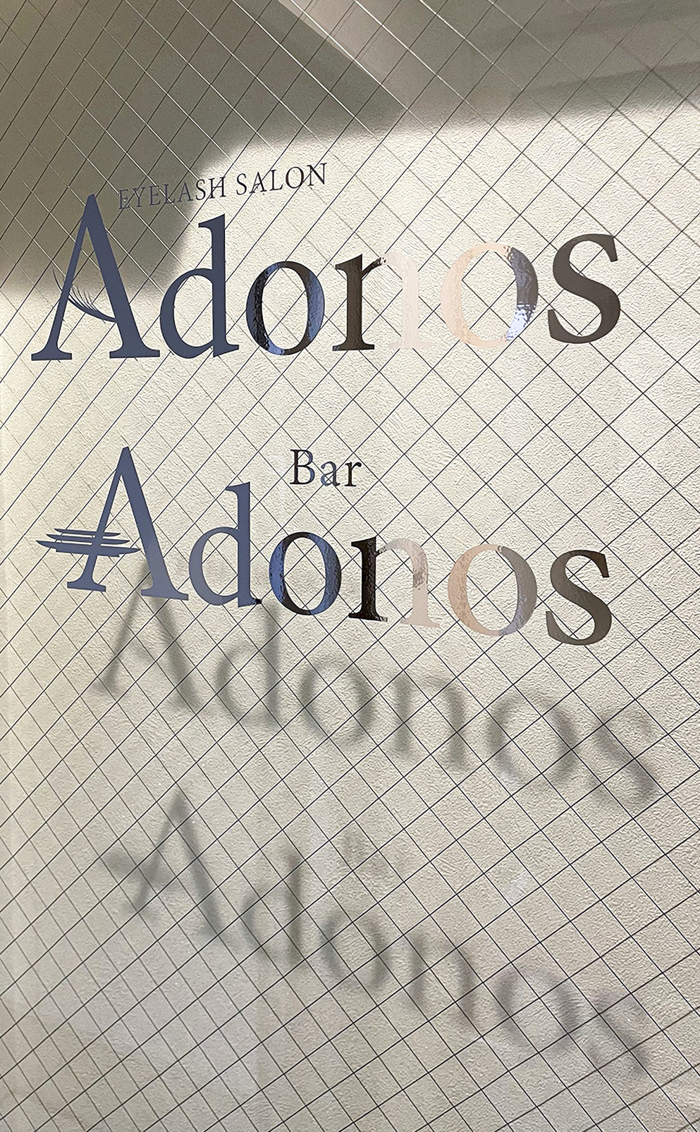 ガラスに貼られた店名のメタリックなカッティングシート