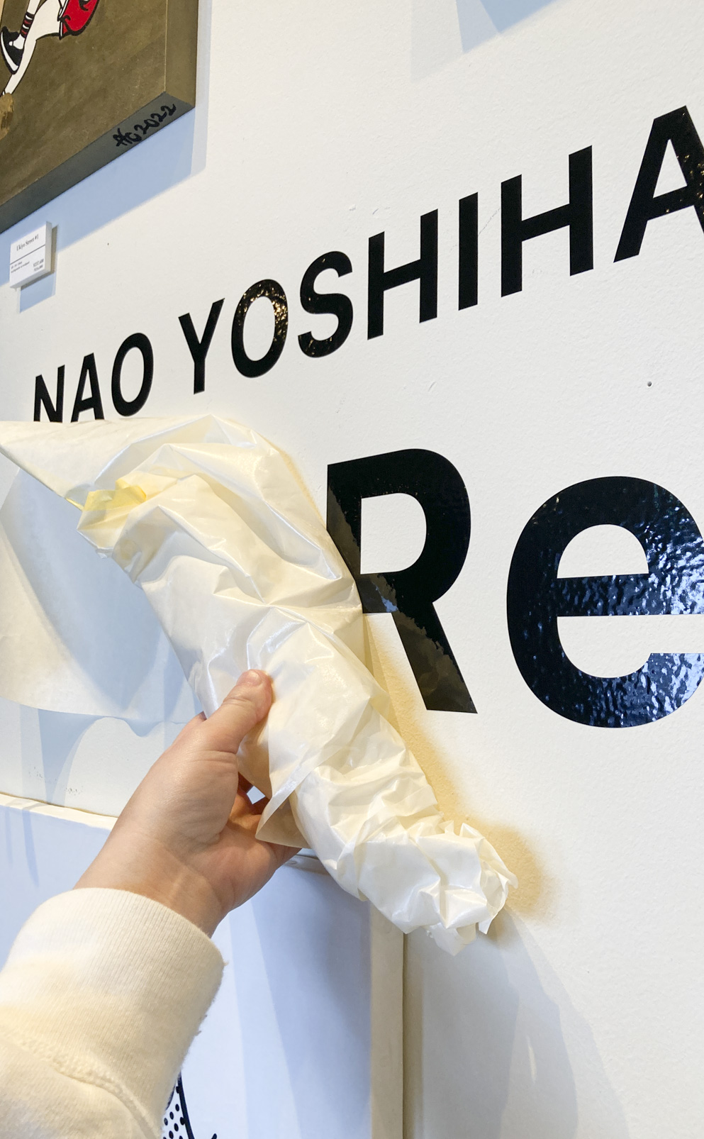 個展会場の壁にカッティングシートを施工中