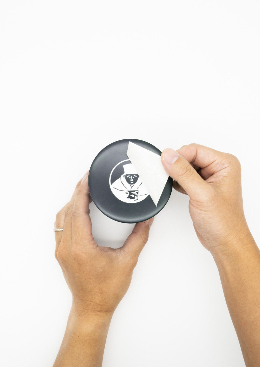 濃緑色の茶筒にイラストデザインのカッティングシートを貼っている