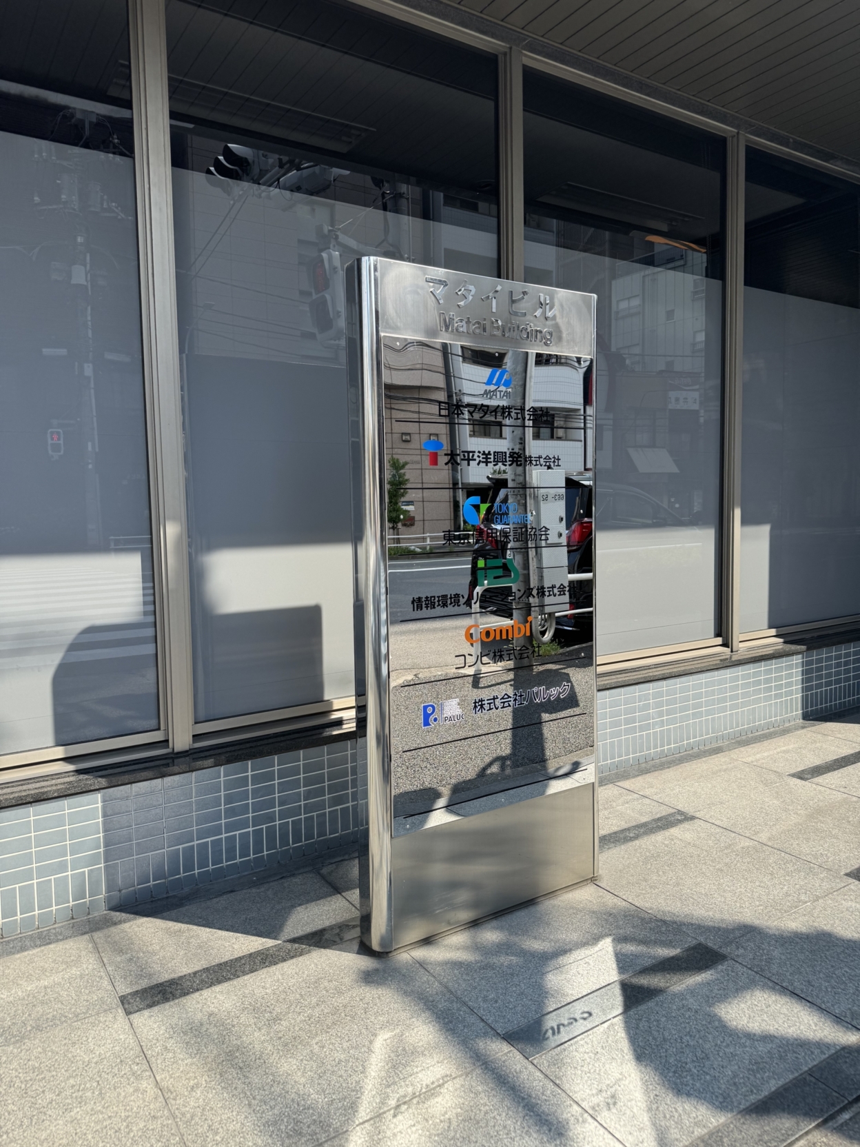 鏡面のビル銘板に貼られた多色のカッティングシートロゴ